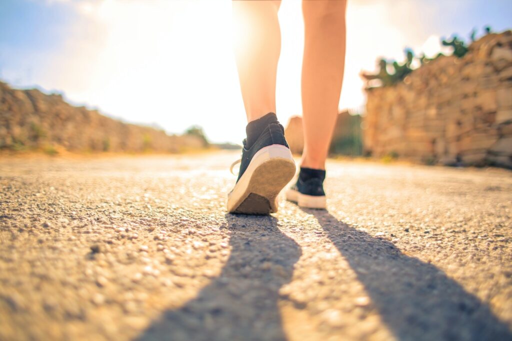 Person walking a path with sun in background.